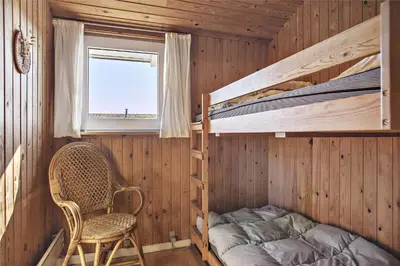 a bedroom with bunk beds and a chair and a window at BL758-Pandrup-Hunetorp-Klitvej-237 in Pandrup