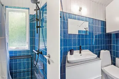 a blue tiled bathroom with a sink and a toilet at BL1494-Saltum-Viborgvej-6 in Saltum