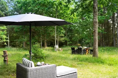 a table with an umbrella and chairs in a field at BL1494-Saltum-Viborgvej-6 in Saltum