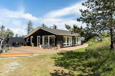 a house with a large wooden deck in front of it at BL1371-Blokhus-Sletten-10-A in Blokhus