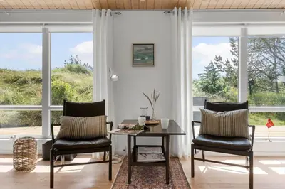 a living room with two chairs and a table and windows at BL1371-Blokhus-Sletten-10-A in Blokhus