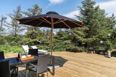 a table with an umbrella on a wooden deck at BL1371-Blokhus-Sletten-10-A in Blokhus