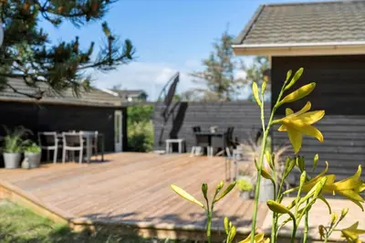 a wooden deck with a table and chairs on it at BL1371-Blokhus-Sletten-10-A in Blokhus