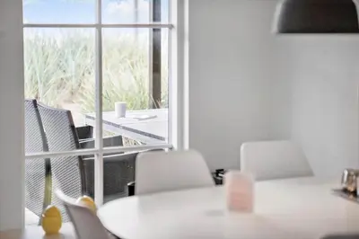 a dining room with a table and chairs and a window at BL1260-Blokhus-Strandvejen-14-Lejl-9 in Blokhus