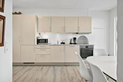 a kitchen with white cabinets and a table and chairs at BL1260-Blokhus-Strandvejen-14-Lejl-9 in Blokhus
