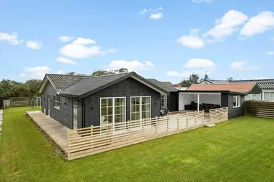 a house with a wooden deck in the yard at BL1246-Blokhus-Vigen-6 in Blokhus
