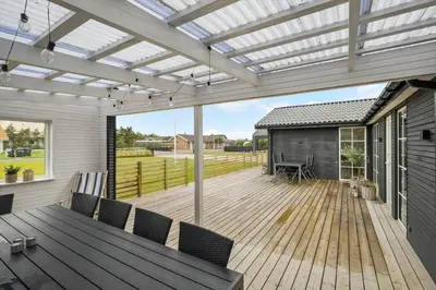 a patio with a wooden deck with a pergola at BL1246-Blokhus-Vigen-6 in Blokhus