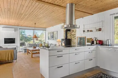 a kitchen with white cabinets and a living room at BL1677-Saltum-Sikahjortvej-6 in Saltum