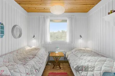 a bedroom with two beds and a table with a window at BL1677-Saltum-Sikahjortvej-6 in Saltum