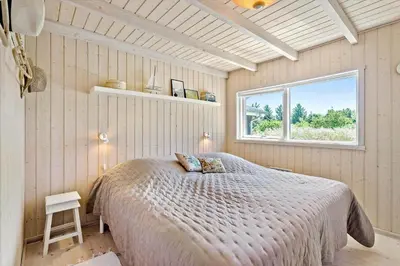 a bedroom with a bed in a room with a window at BL1700-Blokhus-Bloksbjerg-55 in Blokhus