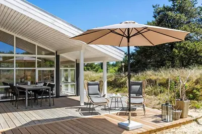 a patio with an umbrella and a table and chairs at BL1700-Blokhus-Bloksbjerg-55 in Blokhus