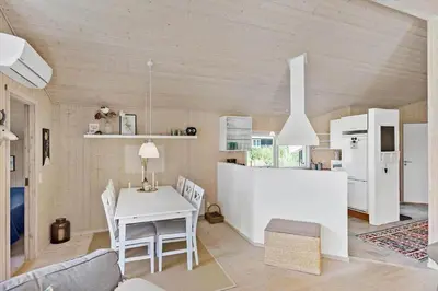 a kitchen and dining room with a white table and chairs at BL1700-Blokhus-Bloksbjerg-55 in Blokhus