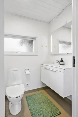 a white bathroom with a toilet and a sink at BL1680-Blokhus-Klitgaardsvej-18 in Blokhus