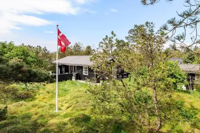 a house on a hill with a red flag at BL1082-Blokhus-Klintevej-12 in Blokhus