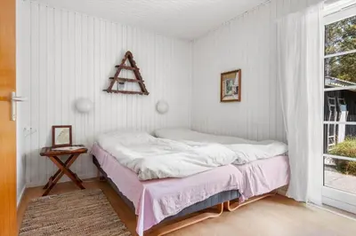 a small bedroom with a bed and a window at BL1082-Blokhus-Klintevej-12 in Blokhus