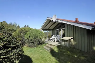 a green house with a bench on the porch at BL1419-Saltum-Skanderborgvej-13 in Saltum