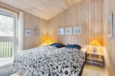 a bedroom with a black and white bed and a window at BL1156-Blokhus-Ankerhusvej-44 in Blokhus