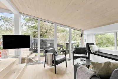 a living room with a flat screen tv and chairs at BL1335-Blokhus-Havorns-Alle-32 in Blokhus