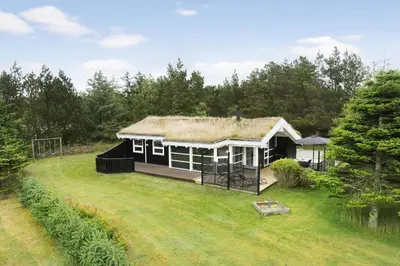 a small house with a grass roof on a yard at BL485-Blokhus-Sandtoften-29 in Blokhus