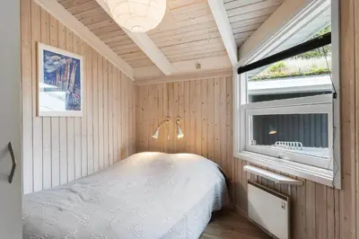 a small bedroom with a bed and a window at BL485-Blokhus-Sandtoften-29 in Blokhus
