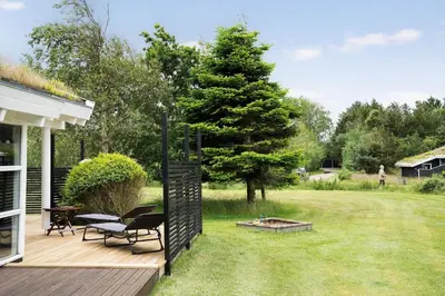 a deck with a chair and a tree in a yard at BL485-Blokhus-Sandtoften-29 in Blokhus