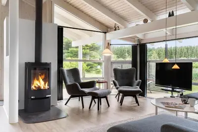 a living room with a fireplace and chairs and a tv at BL485-Blokhus-Sandtoften-29 in Blokhus