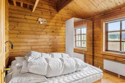 a bedroom with a white bed in a wooden wall at BL1801-Saltum-Kordalsvej-115 in Saltum