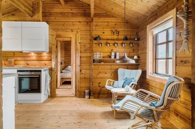 a log cabin kitchen with wooden walls and chairs at BL1801-Saltum-Kordalsvej-115 in Saltum
