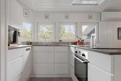 a white kitchen with white cabinets and windows at BL1200-Blokhus-Plantagevej-6-C in Blokhus