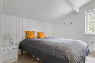 a bedroom with a bed with two orange pillows at BL1200-Blokhus-Plantagevej-6-C in Blokhus