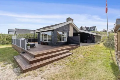 a house with a wooden deck in the yard at BL813-Blokhus-Klitvejen-12 in Blokhus