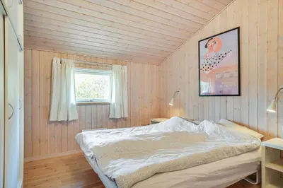 a bedroom with a bed in a room with a window at BL813-Blokhus-Klitvejen-12 in Blokhus