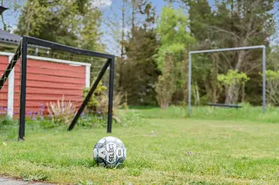 a soccer ball sitting in the grass next to a goal at BL1332-Pandrup-Rodhusparken-78 in Pandrup