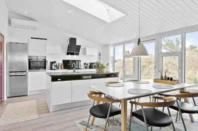 a white kitchen with a table and chairs in it at BL1767-Saltum-Saltum-Strandvej-209 in Saltum