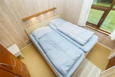 a bed in a small room with a window at BL861-Blokhus-Pirupshvarrevej-49 in Blokhus