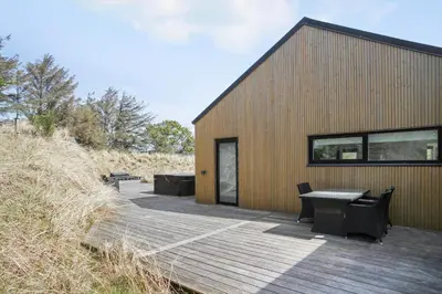 a wooden deck with benches and a building at BL1405-Blokhus-Sletten-12 in Blokhus