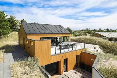 a house with a black roof and a deck at BL1405-Blokhus-Sletten-12 in Blokhus