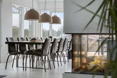 a dining room with a table and chairs and a fireplace at BL1405-Blokhus-Sletten-12 in Blokhus