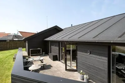 a black house with a patio with a table at BL1573-Blokhus-Soren-Tjenersvej-3 in Blokhus