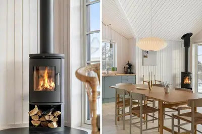 a fireplace in a kitchen and a dining room with a table at BL1324-Blokhus-Pirupshvarrevej-101 in Blokhus