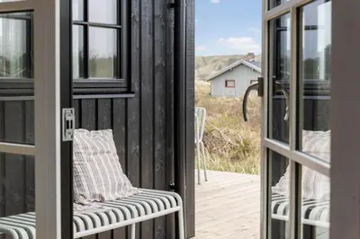 a screened in porch with a chair and a window at BL1324-Blokhus-Pirupshvarrevej-101 in Blokhus
