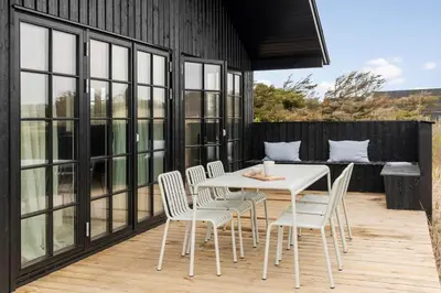 a white table and chairs on a wooden deck at BL1324-Blokhus-Pirupshvarrevej-101 in Blokhus