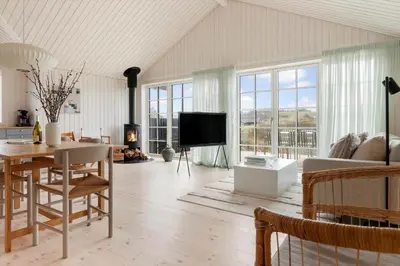 a living room with a dining table and a tv at BL1324-Blokhus-Pirupshvarrevej-101 in Blokhus