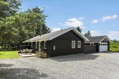 a black house with a picnic table in front of it at BL1205-Blokhus-Quintusvej-26 in Blokhus