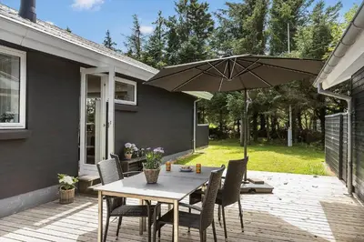 a table and chairs with an umbrella on a patio at BL1205-Blokhus-Quintusvej-26 in Blokhus