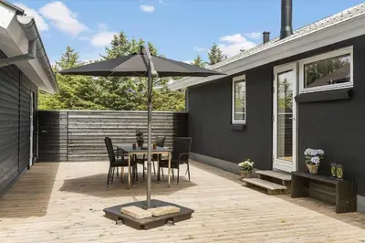 a patio with a table and an umbrella at BL1205-Blokhus-Quintusvej-26 in Blokhus