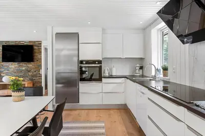 a kitchen with white cabinets and a stainless steel refrigerator at BL1205-Blokhus-Quintusvej-26 in Blokhus