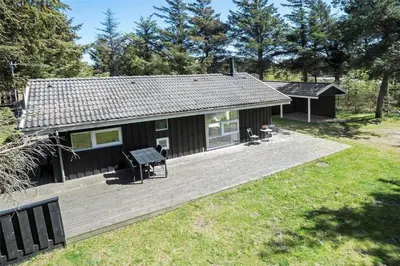 a small house with a wooden deck in a yard at BL583-Saltum-Saltum-Strandvej-210 in Saltum