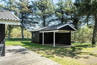 a black shed with a porch next to a wooden deck at BL583-Saltum-Saltum-Strandvej-210 in Saltum
