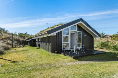 a small house with a porch and chairs in the yard at BL331-Saltum-Ornebjergvej-21 in Saltum